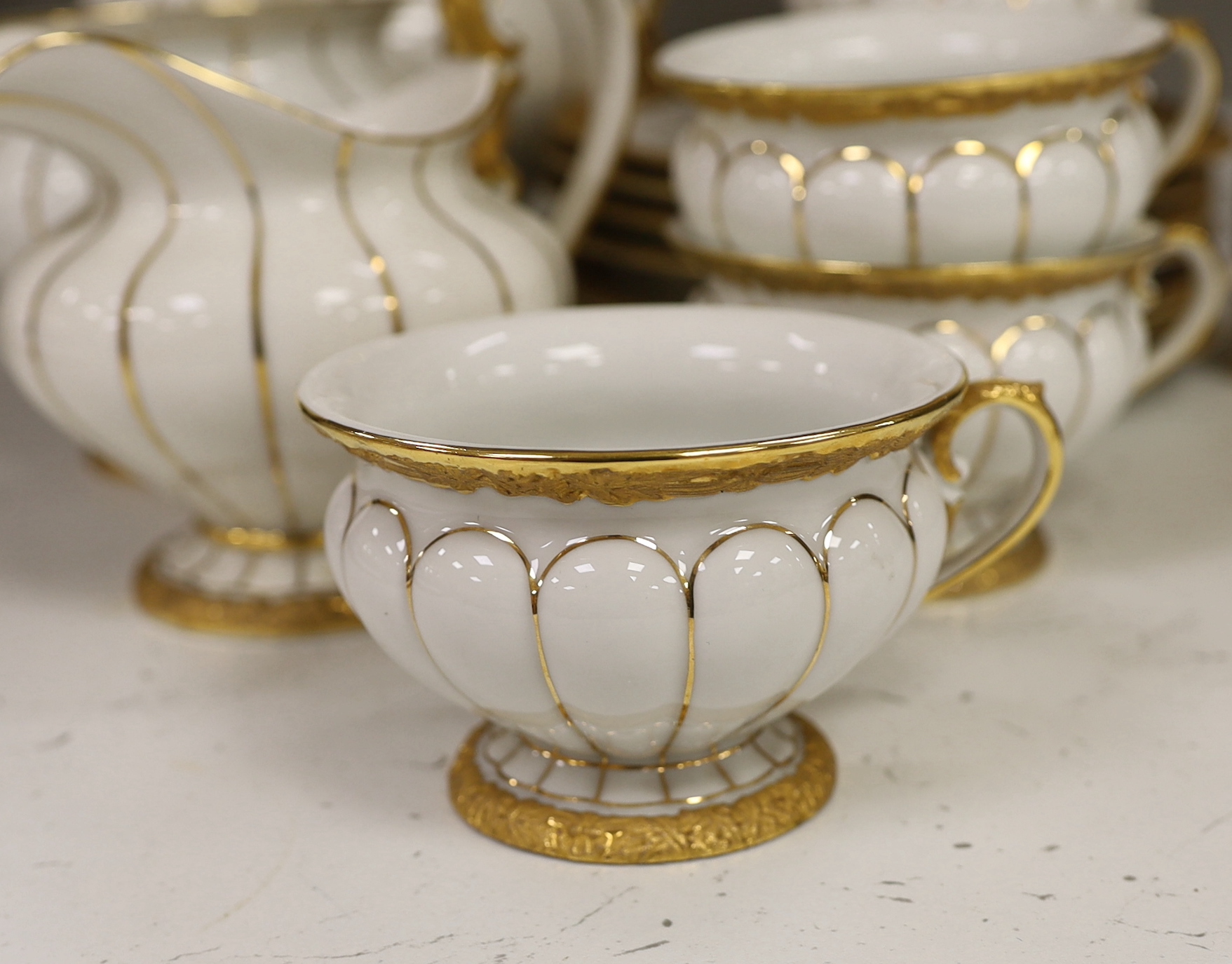 A Meissen gilt and white glazed porcelain tea service, mid 20th century, comprising a teapot, coffee pot, sugar bowl, side plates and seven cups and saucers, coffee pot 28cm